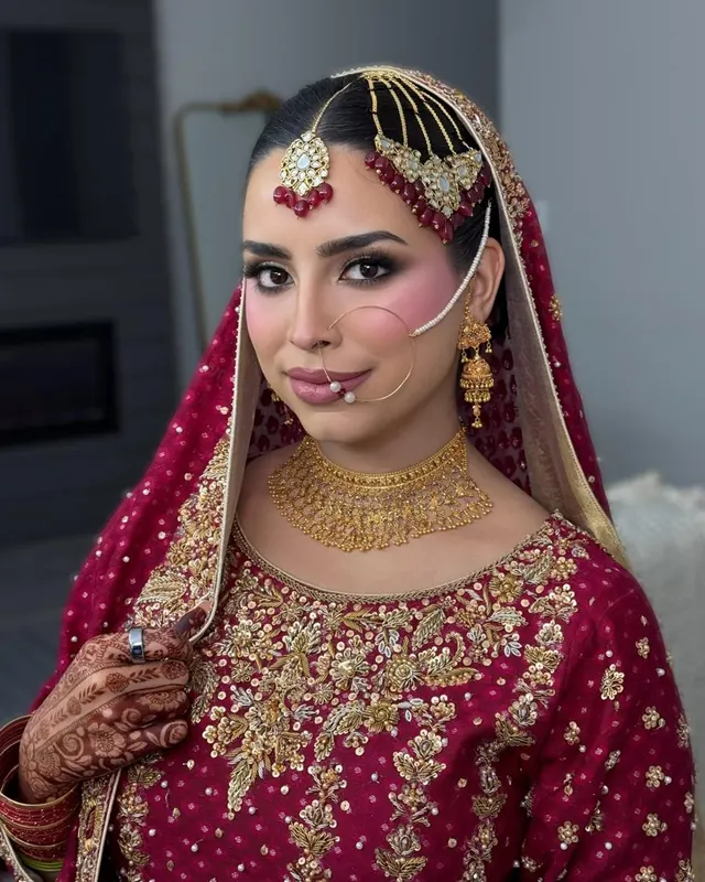 Bride in red with gold jewellery and mehndi, makeup by Samia